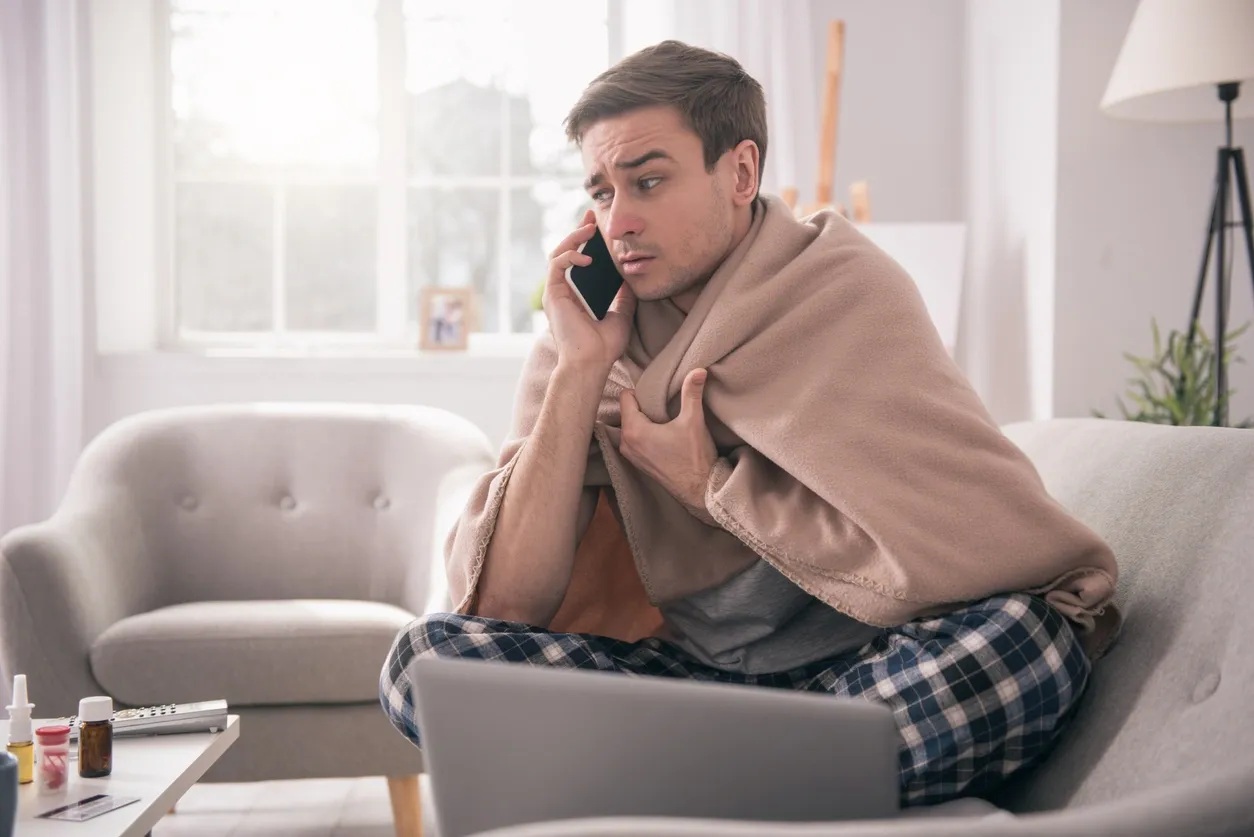 Man on a phone wrapped in a blanket